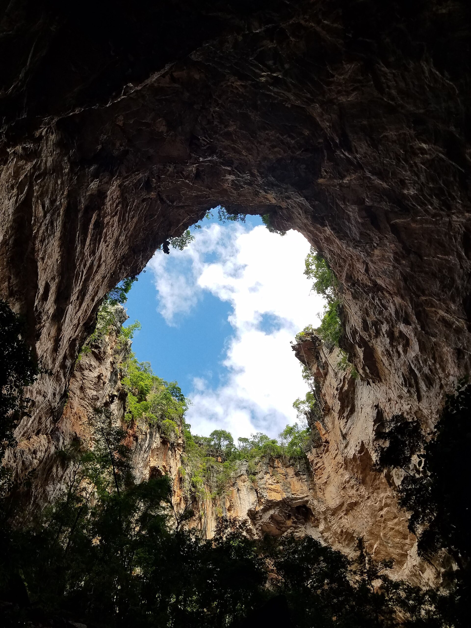 Natural skylight opening in the ceiling of a Peruaçu cave, seen from below against the blue sky